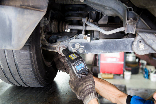 Mechanic adjusting the screw during wheel alignment process