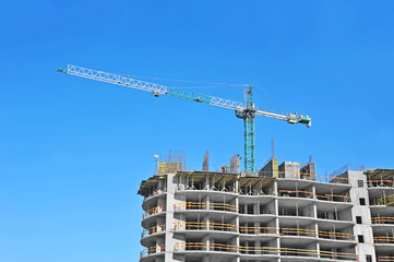 Crane and building construction site against blue sky