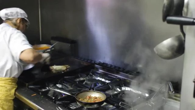 chef cooking pasta with fish at italian restaurant