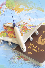 Toy plane resting on a thailand passport and world map