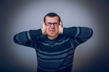 Naklejka premium European-looking male covering his ears with hands brunet