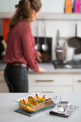 Closeup on pan of baked pumpkin and housewife in background