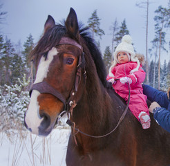 Baby girl horseback riding at winter