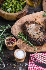 Grilled medium rare beef steak with herbs on rustic table