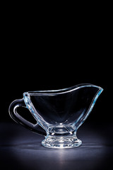 glass transparent gravy boat on black background