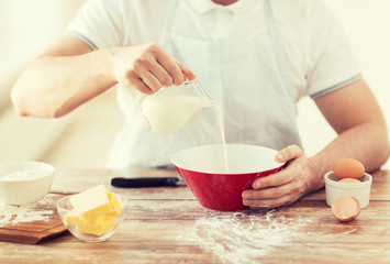 Obraz na płótnie Canvas close up of male hand pouring milk in bowl