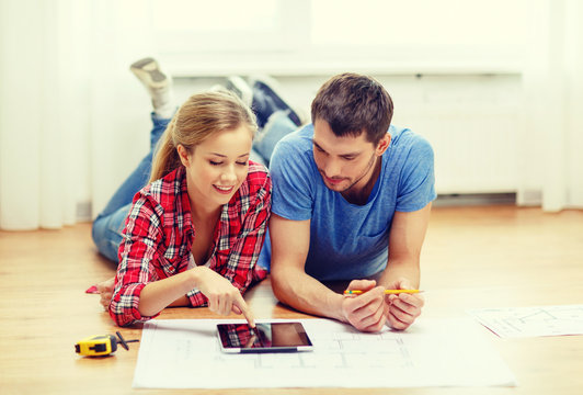 smiling couple looking at tablet pc at home