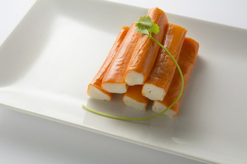 Surimi or crab sticks in a white rectangular plate. . White back
