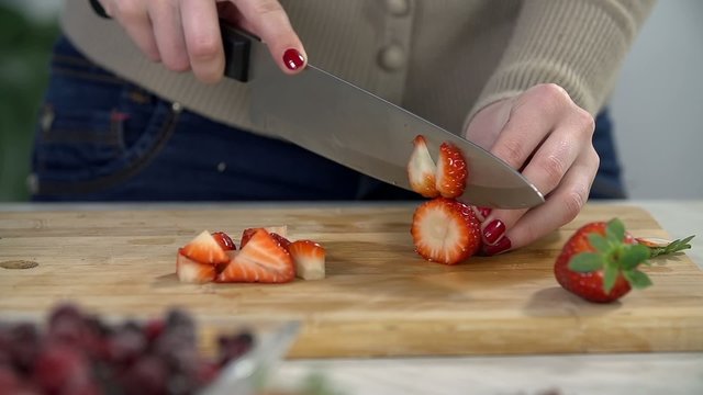Slicing the strawberry on a wooden desk