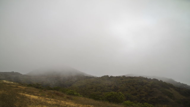 Time lapse of clouds rolling over green hills