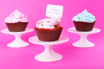 Delicious cupcakes with inscription on color background