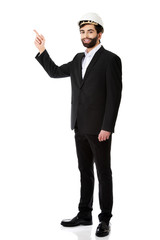 Engineer in protective helmet pointing up.