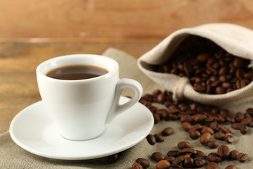 Cup of coffee with beans on rustic wooden background