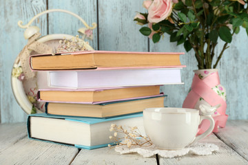 Cup of tea with books and flowers on wooden background