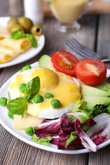 Toast with egg Benedict and avocado on plate on wooden table