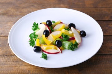 Waldorf salad with olive on plate on wooden background