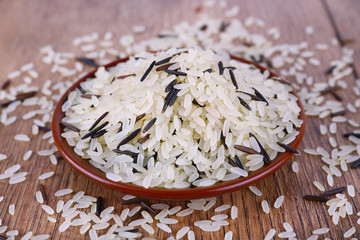 Obraz na płótnie Canvas Grain of rice on plate on wooden background