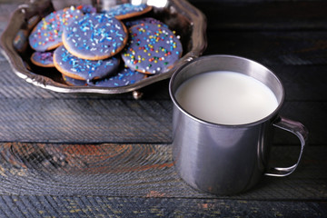 Glazed cookies in metal bowl and mug of milk