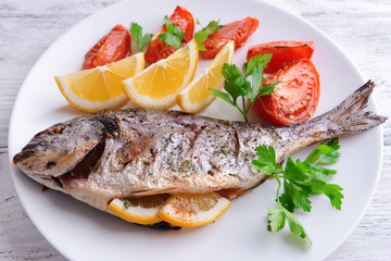 Tasty baked fish on table close-up