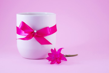 White coffee mug decorated with a pink ribbon