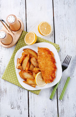Breaded fried fish fillet and potatoes with sliced lemon