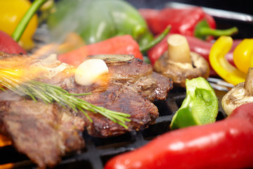 T-bone steak on the barbecue grill with vegetable spears in the