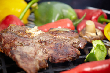 T-bone steak on the barbecue grill with vegetable spears in the