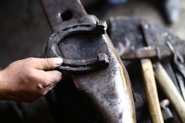 Hand holding a horseshoe on an anvil