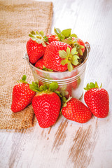 Spring fruits, strawberries in an aluminum bucket on a vintage w