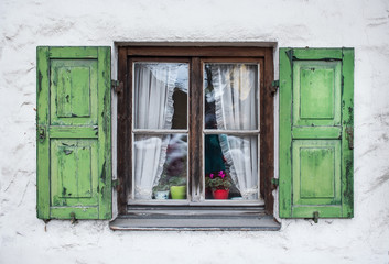 Fototapeta na wymiar Authentic window with green wooden shuttters in a small town of