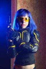 Fototapeta na wymiar Beautiful girl with blue hair holding gun in strikeball location