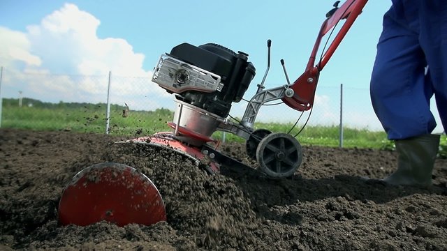 Low angle cultivator thrashing soil close up slow motion
