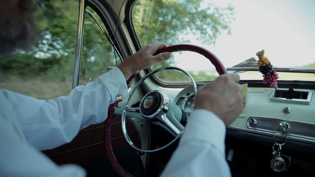 Guy turning a steering wheel in vintage car 
