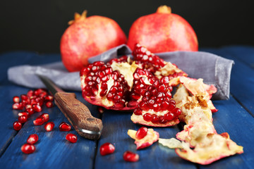 Juicy ripe pomegranates on wooden table, on dark background