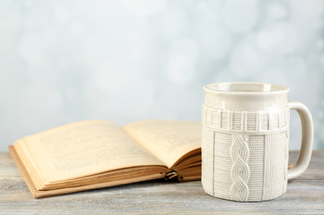 Cup of tea and book on table, on light background