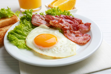 Bacon and eggs on color wooden table background