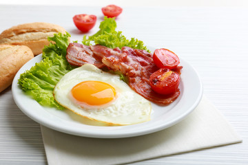 Bacon and eggs on color wooden table background