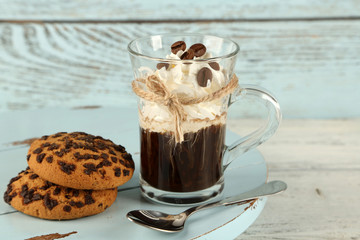Cup of coffee with cream and cookies on wooden background