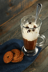 Cup of coffee with cream and cookies on wooden background