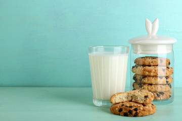 Tasty cookies and glass of milk on color wooden background