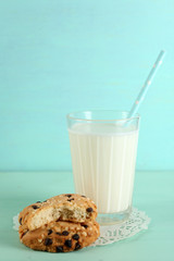 Tasty cookies and glass of milk on color wooden background