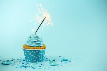 Cupcake with sparkler on blue background