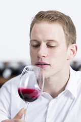 young man shaking a red wine glass.
