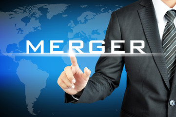 Businessman hand pointing to MERGER sign on virtual screen