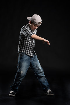 little break dancer showing his skills on black background.