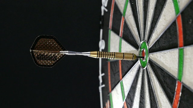Close up of a single dart hitting the bull's eye on a dart board