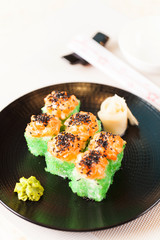 Salmon and caviar rolls served on plate.