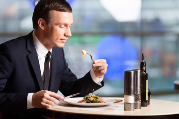 Handsome man eating at restaurant inside.