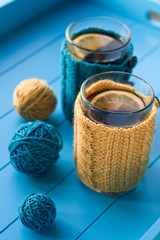 Fototapeta na wymiar Two cups of tea in yellow Knitted sweaters on blue background