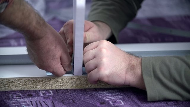 Two guys inserting the nails into the bed frame